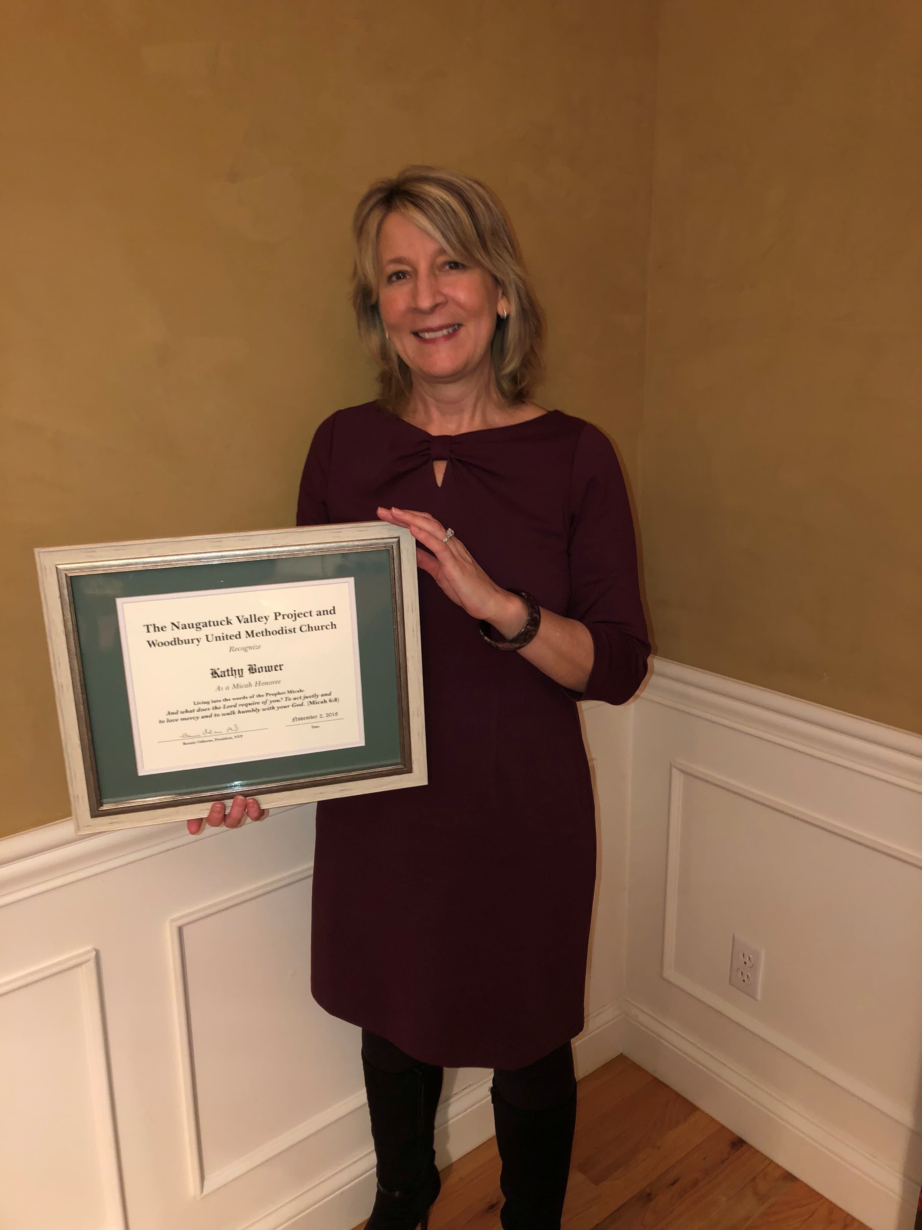 Kathy Bower holding a framed Micah Honoree certificate from the Naugatuck Valley Project and Woodbury United Methodist Church