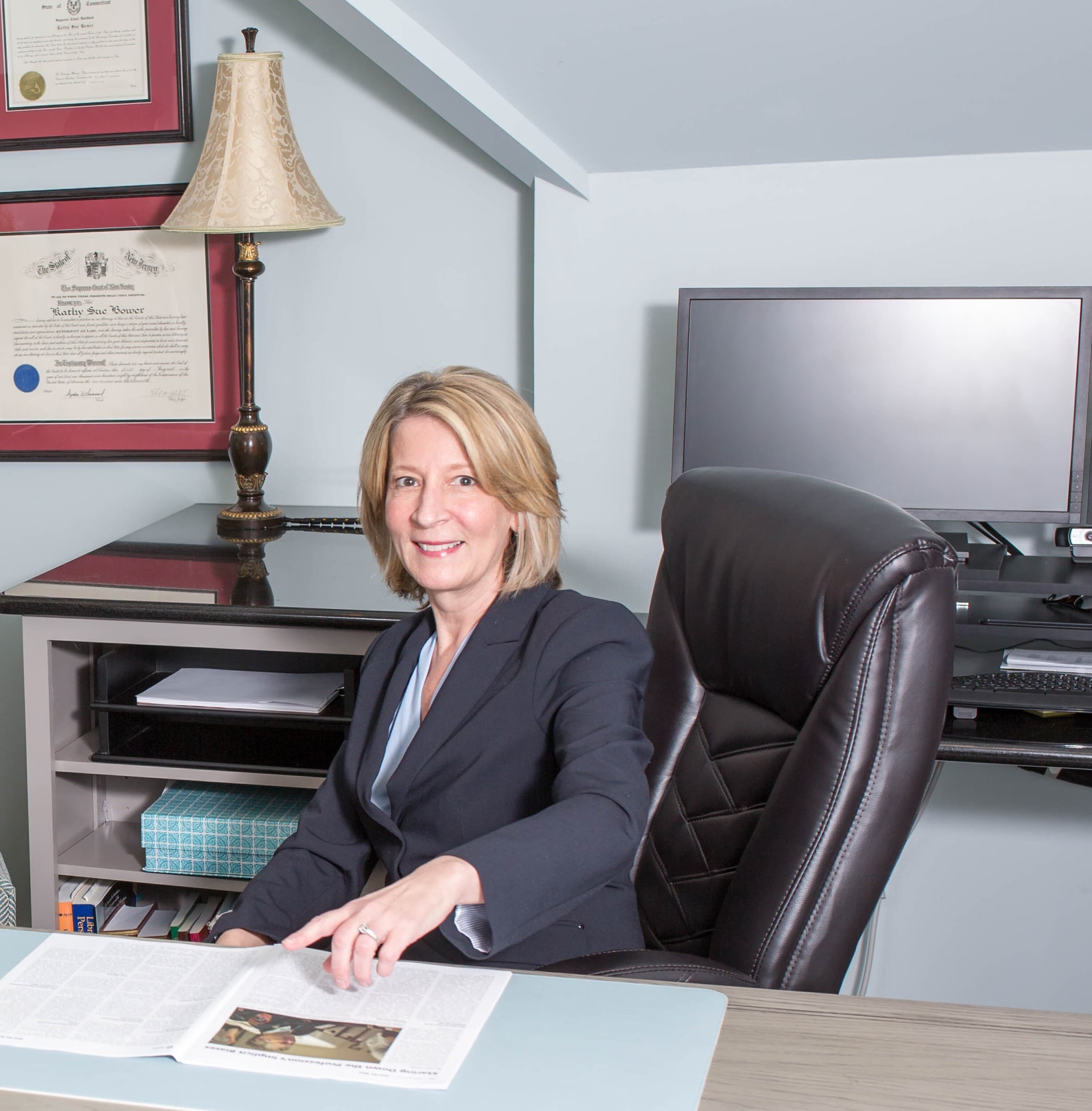 Kathy S. Bower seated at her office desk with client materials